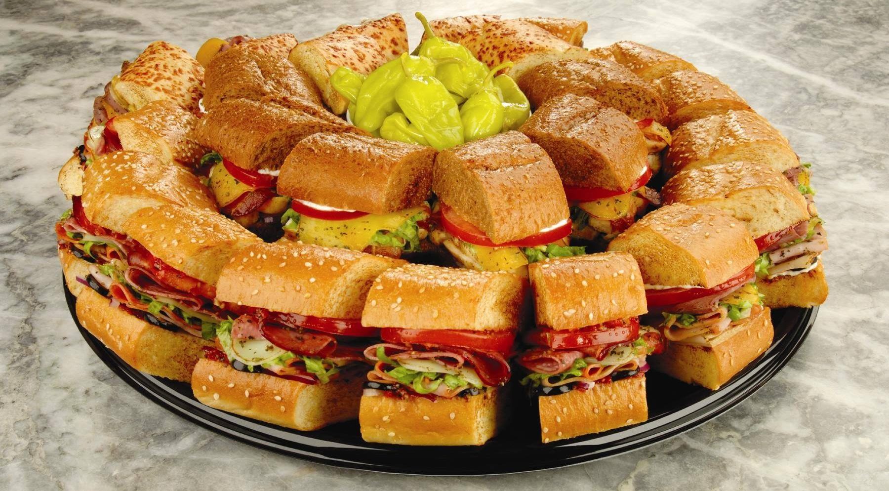 A tray full of sandwiches on a marble table.